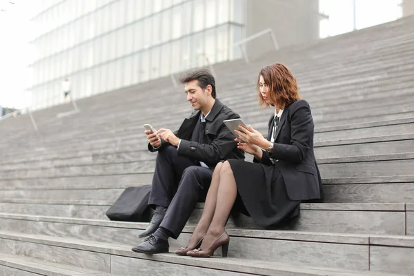 male and female office workers spend break sitting on stair