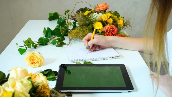 Shooting close-up of hands of female florist with tablet that 's — стоковое фото