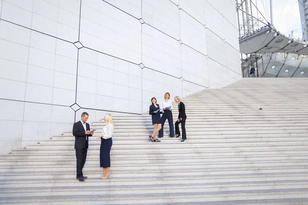 Financial team going down stairs in   with tablet, case and talk