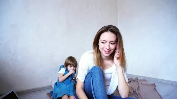 Очаровательная женщина и молодая мать разговаривают по телефону на заднем плане — стоковое фото