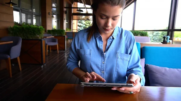 Chica bonita trabajando con la tableta en la cafetería . — Foto de Stock