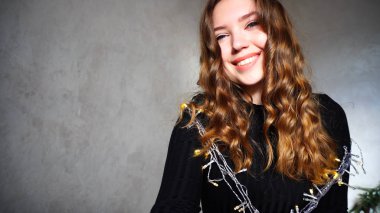 Genç kadın kıvırcık saçlı kameraya bakarak gülümseyen,