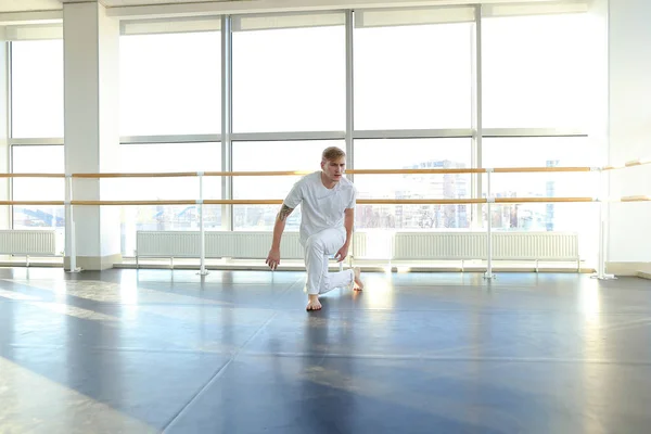 Male person doing one arm handstand with legs spread out.