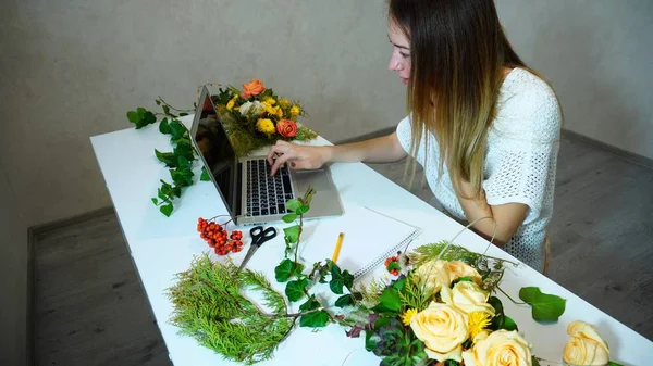 Leuke bloemen meisje maakt gebruik van laptop voor meer informatie over stroom — Stockfoto