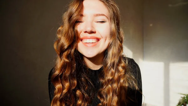 Mujer joven sonriendo, mirando a la cámara con el pelo rizado — Foto de Stock