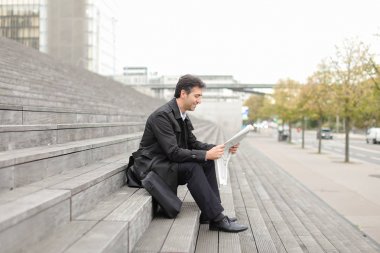     merdivenlerde oturan ve gazete okuyan erkek iş öğretmen