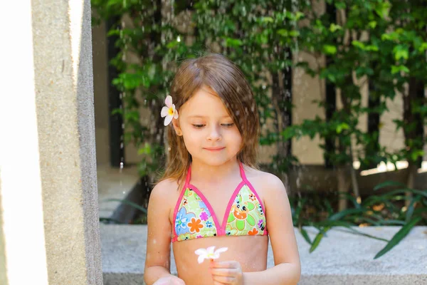 Niña en traje de baño tomando ducha, gotas de agua caen en su — Foto de Stock