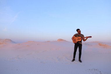 Gitar ayakta bottomle ortasında oynayan yakışıklı erkek Arap