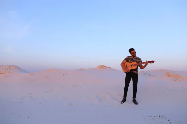 Gutaussehender arabischer Mann, der mitten auf dem Boden stehend Gitarre spielt — Stockfoto