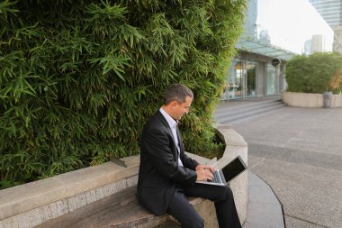 İşadamı çevre bitki dışarıda dizüstü bilgisayar ile çalışma  .