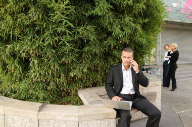 Smartphone ile konuşmak ve içinde dışında laptop ile çalışan Yöneticisi