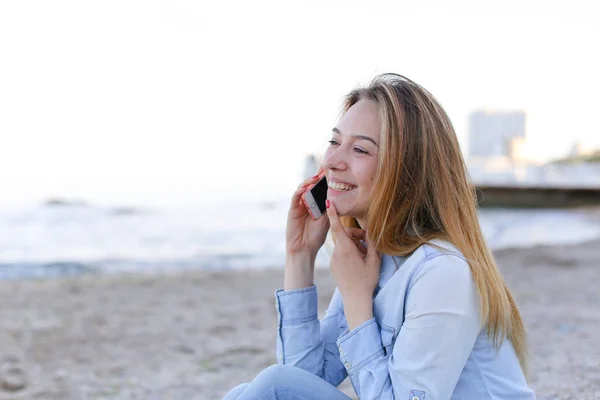 Beautiful portrait of female speaks on mobile with smile and sit