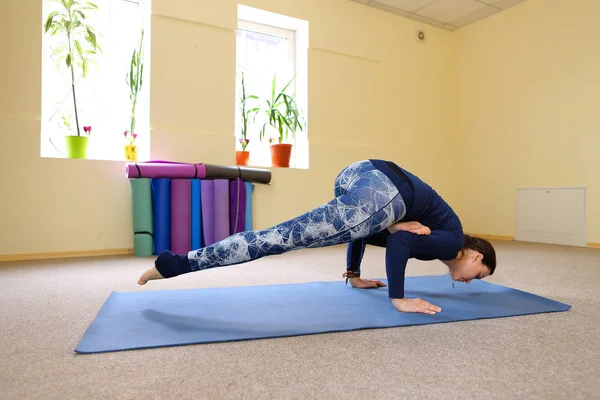 Menina europeia de cabelos escuros fazendo aquecimento na sala de fitness espaçosa — Fotografia de Stock