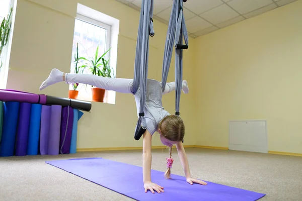 Schoolgirl sits on twine on acrobatic ropes.