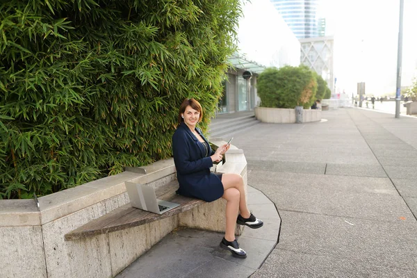 Geschäftsfrau tippt Nachricht und hört Musik draußen mit — Stockfoto