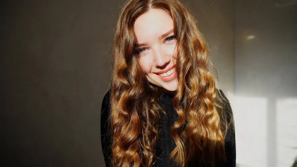 Mujer joven sonriendo, mirando a la cámara con el pelo rizado — Foto de Stock
