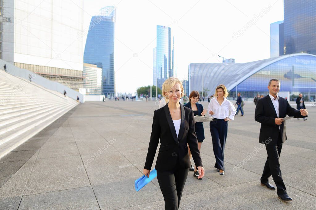Businesswoman from back passing in   with blue document case in 