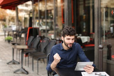 Hoşnutsuz adam online oyun tarafından tablet sokak café'de oynuyor..