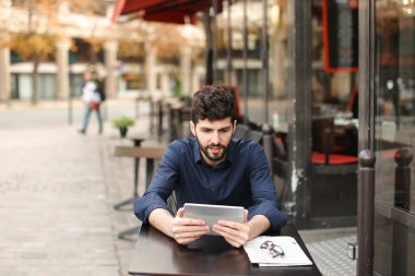 Hoşnutsuz adam online oyun tarafından tablet sokak café'de oynuyor..