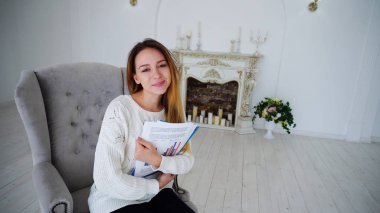 Kağıtları ve gülümseyen ve sandalyede oturan klasörlerle, poz kız öğrenci