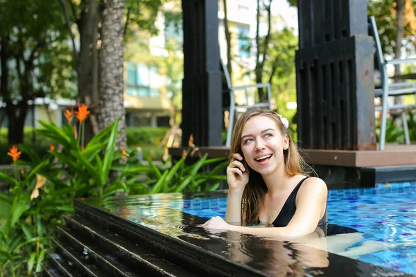 プールで水泳のスマート フォンで話している幸せな女 — ストック写真