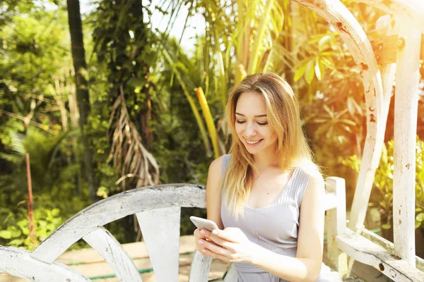 Mujer rubia escribiendo teléfono inteligente para el trabajo en el día soleado, fondo de palmas verdes sol en Tailandia, viajes Phuket — Foto de Stock