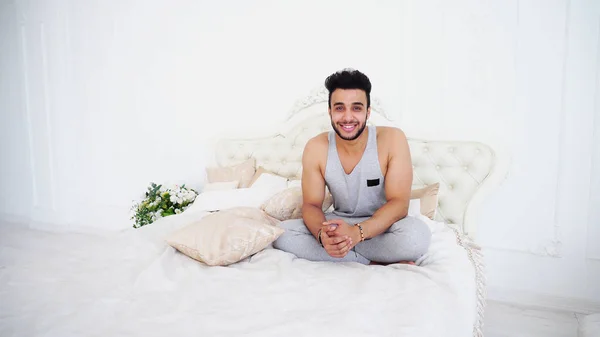 Jonge Arabische Man ontspant en glimlacht terwijl liggend op Bed in Bright B — Stockfoto