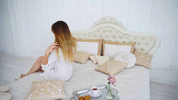 Jonge vrouw gelukkig met staat van haar, zitten met rug naar Camera op zachte Bed — Stockfoto