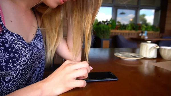 Cerca de las manos femeninas utilizando el teléfono inteligente en el restaurante . — Foto de Stock