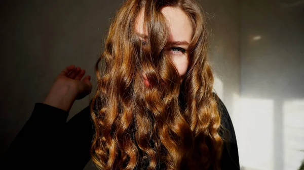 Mujer joven sonriendo, mirando a la cámara con el pelo rizado —  Fotos de Stock