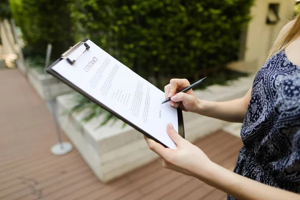 Retrato cercano de la mujer firma contrato en el fondo del edificio — Foto de Stock