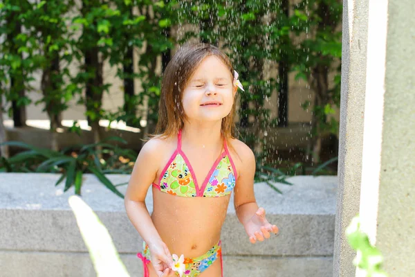 Gotas de agua caen, niña en traje de baño tomar ducha en el sol — Foto de Stock
