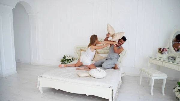 Счастливая пара ведет себя как дети на кровати в светлом доме . — стоковое фото