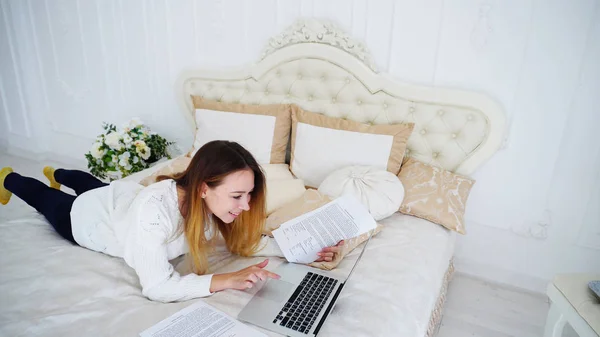 Vrouwelijke Student doet huiswerk op de Computer en leest informatie op papier liggen — Stockfoto