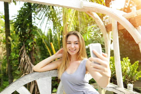 Woman taking photo selfie on smart phone on sunny day, background of sunshine green palms in Thailand, Phuket — Stock Photo, Image