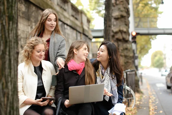 Kvinnliga studenter som sitter på bänken och lärande med laptop och pa — Stockfoto