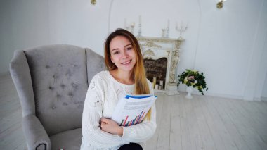 Kağıtları ve gülümseyen ve sandalyede oturan klasörlerle, poz kız öğrenci