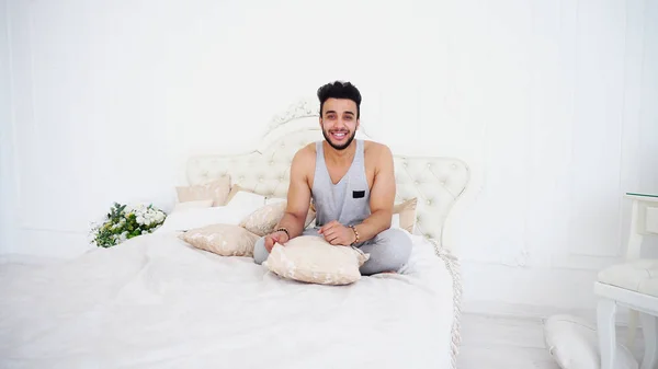 Joven árabe se relaja y sonríe mientras está acostado en la cama en Bright B — Foto de Stock