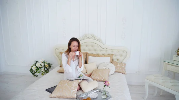 Huisvrouw drinken thee, om thuis te zitten op het grote Bed — Stockfoto
