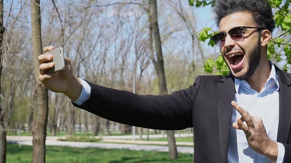 Muslimischer Junge testet neues Handy und zeigt Friedenszeichen Hand — Stockfoto