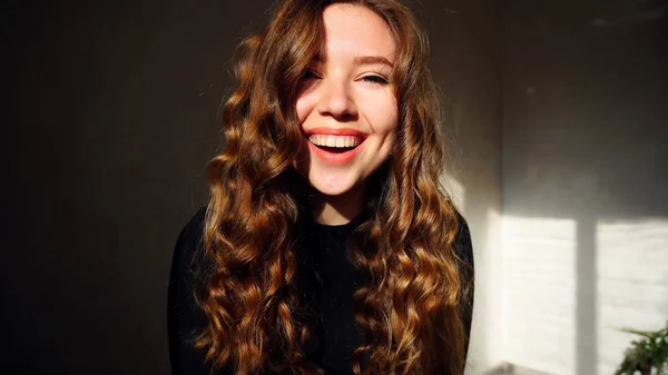 Genç kadın kıvırcık saçlı kameraya bakarak gülümseyen, — Stok fotoğraf