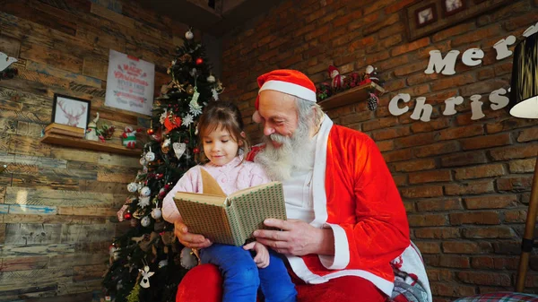 Niña europea sentada de rodillas en Santa Claus . — Foto de Stock