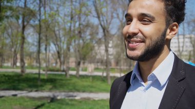 İşten sonra parkta yürüyen stajyer yüzündeki gamzeler ile gülümseyen