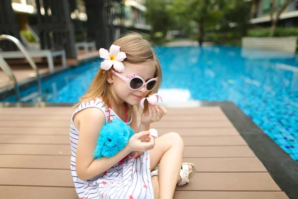 Закрыть маленький ребенок сидит рядом с бассейном носить sungl — стоковое фото