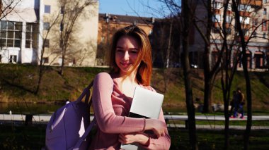 Mutlu öğrenci dizüstü bilgisayar ve sırt çantası parkta yürüyüş .