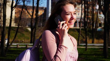 Parkta yürümek ve konuşmak smartphone tarafından neşeli öğrenci.