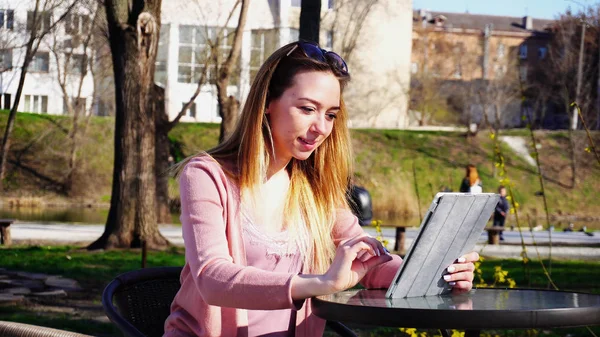 Belle femme bavarder avec des amis par tablette dans le parc . — Photo