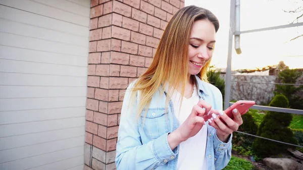 Chica joven con cerca de escribir las manos por teléfono inteligente de pie nea — Foto de Stock