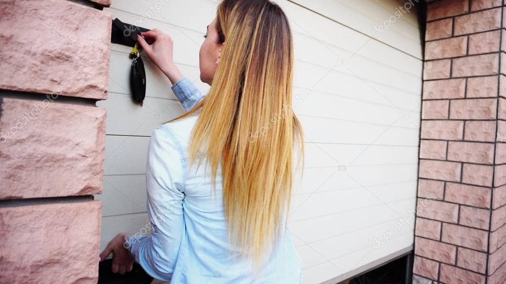 Young female person opening garage door with keys.