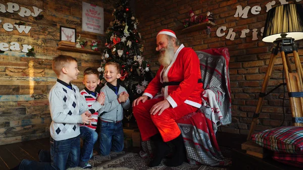 Tres niños pequeños le piden a Santa Claus que cuente la historia de los elfos — Foto de Stock